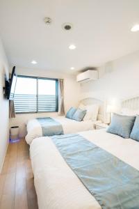 un dormitorio con dos camas y un sofá en Oceanfront Villa Hale Kahakai - Vacation STAY 52109v, en Miura