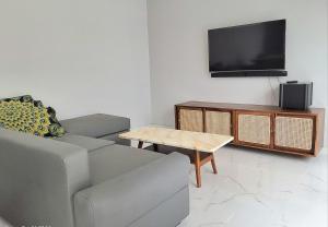 a living room with a couch and a flat screen tv at Near to The Beach Ayunjani Villa, Bali in Ketewel