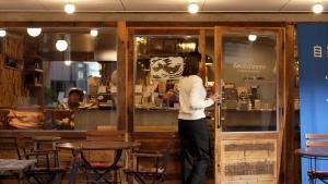 Eine Frau steht in einem Restaurant und schaut ins Fenster. in der Unterkunft COFFEE HOTEL Soundwave - Vacation STAY 17826v in Fujisawa