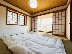 TaikiにあるMidoricho Guest House - Vacation STAY 15204の窓2つが備わる客室で、白い大型ベッド1台が付いています。