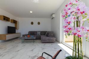 a living room with a couch and pink flowers at Apartments Sanela in Veliko Brdo
