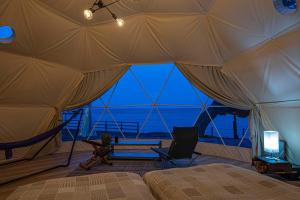 a bedroom with a tent with a view of the ocean at Glamping & Villa La-gom - Vacation STAY 82914v in Inatori +6 photos