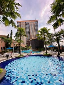 a large pool with palm trees in front of a hotel at Luxy Service Apartment at Times Square KL in Kuala Lumpur