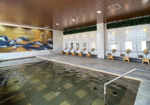 a swimming pool with tables and chairs in a building at Glamping Base IZUMO "Lakeside Hot Spring Hotel Kun - Vacation STAY 42024v in Izumo