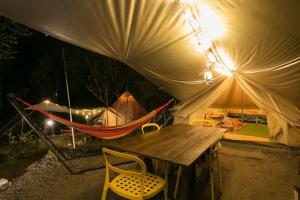 une tente avec une table et un hamac à l'intérieur dans l'établissement Shirasu-Ojiro FLORA Campsite in the Natural Garden - Vacation STAY 00655v, à Shirasu