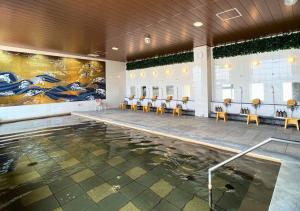 a swimming pool with tables and chairs in a building at Glamping Base IZUMO "Lakeside Hot Spring Hotel Kun - Vacation STAY 42016v in Izumo