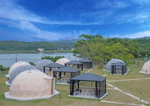 a group of tents in a field next to a lake at Glamping Base IZUMO "Lakeside Hot Spring Hotel Kun - Vacation STAY 42023v in Izumo