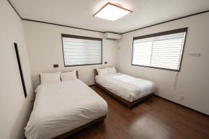 two beds in a room with two windows at Twilight Hills - Vacation STAY 32702v in Motobu