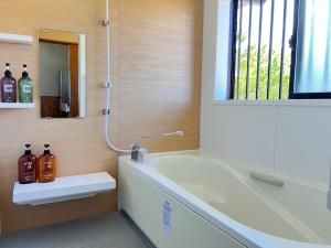 a bathroom with a tub and a sink and a mirror at Inori Resort SORAKAZE - Vacation STAY 49443v in Shushi