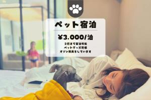 a woman laying in bed next to a dog at Inori Resort SORAKAZE - Vacation STAY 49443v in Shushi