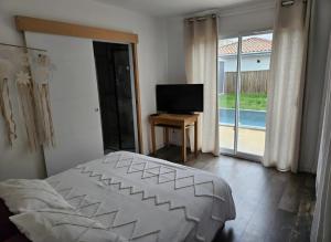 a bedroom with a bed and a television and a balcony at Charmante maison de vacances in Saint-André-de-Cubzac
