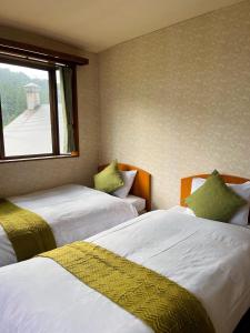 two beds in a room with a window at Yuzawa Hotel New Fukudaya-ski in ski out in Minami Uonuma +10 photos