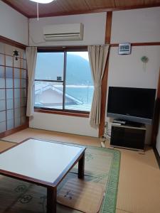 a living room with a table and a tv at Bayside House Shiosai - Vacation STAY 15343 in Kumano