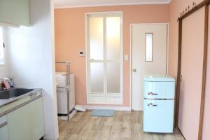 a kitchen with a white refrigerator and a door at blue dot aoshima beach house - Vacation STAY 15358 in Miyazaki +19 photos
