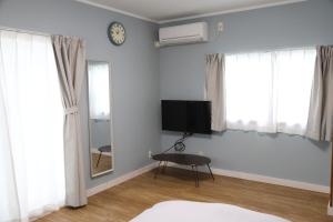 a room with a tv and a table and windows at blue dot aoshima beach house - Vacation STAY 15358 in Miyazaki
