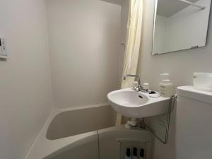 a white bathroom with a sink and a bath tub at K-style Nishijin backpackers - Vacation STAY 17739 in Kyoto