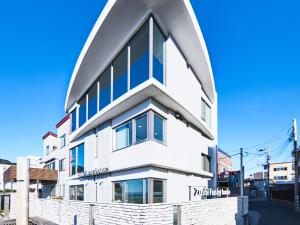 a white building with blue windows on a street at ZUSHI funny house - Vacation STAY 68820v in Zushi