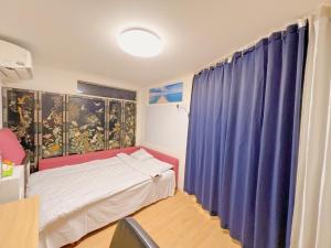 ein Schlafzimmer mit einem Bett und einem blauen Vorhang in der Unterkunft JINGHOUSE Takasago detached house - Vacation STAY 17050 in Tokio