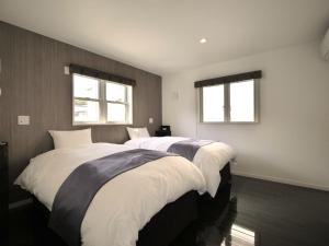two beds in a room with two windows at MIYAZAKI BASE in aoshima - Vacation STAY 82721v in Miyazaki +14 photos