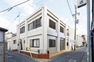 a white building with black shuttered windows on a street at BBQ & Residence Tokoname - Vacation STAY 86709v in Tokoname