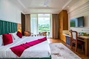 a hotel room with a large bed with a desk at Hotel C7 Munnar in Munnar