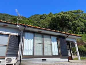 a house with windows with a mountain in the background at Guesthouse Kirishima - Vacation STAY 02754v in Kirishima