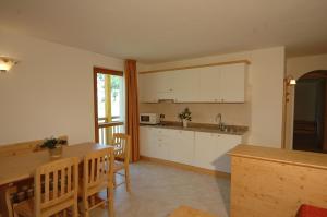 a kitchen with white cabinets and a table and chairs at Tana Della Volpe in Lavarone