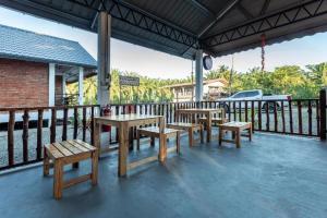 a group of tables and benches on a patio at OYO 90149 Pua Family Semporna in Bulingisan