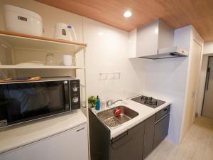 a small kitchen with a microwave and a sink at REVISION Kairouyama-tei - Vacation STAY 15800 in Hiroshima