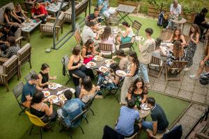 Eine Gruppe von Menschen sitzt an Tischen und isst Essen in der Unterkunft MCC Hostel in Celje