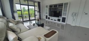 un salon avec un canapé blanc et une télévision dans l'établissement Harary Family apartments, à Amphoe Sawang Daen Din