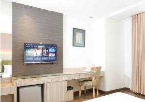 a room with a desk with a tv on a wall at Hotel Wisata Niaga in Purwokerto