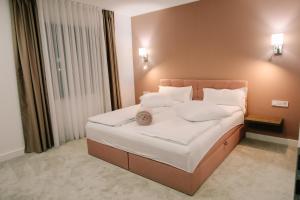 a bedroom with a large bed with white sheets and pillows at The Butterfly in Sângeorgiu de Mureș