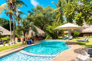 a pool with chairs and an umbrella and palm trees at Vila la Mar Vilanculo in Vilanculos