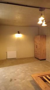 an empty room with two lights and a wooden cabinet at IO House in Urekis Sadguri