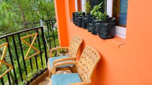 2 sedie sedute su un balcone accanto a una finestra di Mayank homestay shimla a Shimla