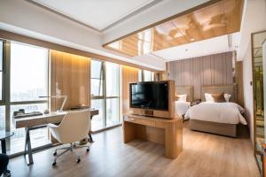 a bedroom with a bed and a desk with a television at 郑州豪锦汇酒店 Zhengzhou Haojinhui Hotel in Zhengzhou