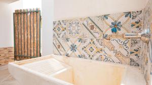 a bath tub in a room with a tile wall at Villino Maria in Triscina +15 photos