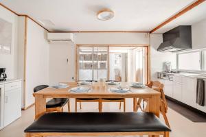 eine Küche und ein Esszimmer mit einem Holztisch und Stühlen in der Unterkunft Kayo BASE in Nago
