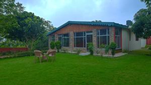 a house with two chairs and a table in a yard at Rudraksha Villa Bhimtal in Bhīm Tāl