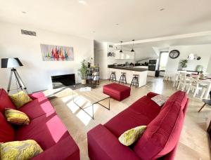 a living room with a red couch and a kitchen at Résidence Le Jardin d'Eugénie in Sanary-sur-Mer