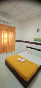 Una cama en una habitación con una manta amarilla. en E657 SERi TERUNTUM, en Kuantan