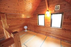 a room with wooden walls and windows in a log cabin at Tokashiki Guest House in Tokashiki