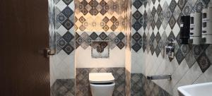 a bathroom with a toilet and a tiled wall at M-Hotel Aman Residency Ops- Quest Mall Near park circus Seven point crossing in Kolkata