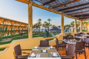 a restaurant with tables and chairs and a view of the ocean at Posada Real Los Cabos in San José del Cabo