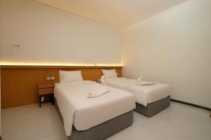 a hotel room with two beds with white sheets at Lume Stay by Sinergi in Achmad Yani International