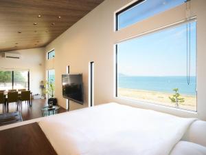 明石市T.Square的一间卧室设有俯瞰海滩的大窗户