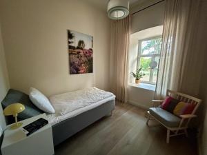 a bedroom with a bed and a chair and a window at Kalnamuiža Apartments in Smiltene