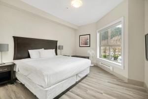 une chambre blanche avec un grand lit et une fenêtre dans l'établissement 2BR Lakefront Lux Escape!, à Harrison Hot Springs