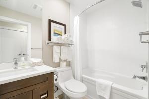 La salle de bains blanche est pourvue d'un lavabo, de toilettes et d'une baignoire. dans l'établissement 2BR Lakefront Lux Escape!, à Harrison Hot Springs 23 autres photos
